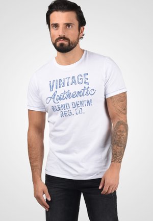 Bijela pamučna majica s natpisom 'VINTAGE Authentic Blend Denim REG. CO.' u plavim slovima. Kratki rukavi, okrugli izrez i slobodan kroj.