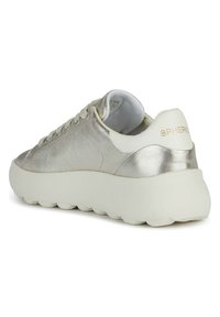 Zapatilla metálica plateada con una superficie texturizada, suela blanca suave y un branding sutil en el talón. Presenta cordones redondeados y una lengüeta acolchada.