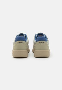 Baskets pour hommes avec dessus en cuir beige, accents bleus, semelle texturée et logo au talon ; design profil bas avec fermeture à lacets.