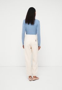 Svetlomodrý sveter, krémové voľné nohavice s zadným vreckom a mäkké ružové nazúvacie topánky. Jemné textúry s jednoduchým dizajnom.