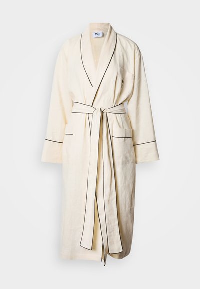 Bēša linu halāts ar melnu apmali šuvju garumā, jostu un divām priekšējām kabatām. Garas piedurknes un šāls apkakles dizains.