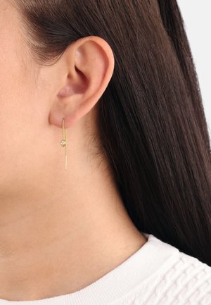 Orecchini a goccia color oro con una sottile barra verticale che presenta un piccolo gemma trasparente, appesi delicatamente dal lobo dell'orecchio.