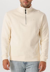 Beige pullover sweatshirt met een halve rits kraag, lange mouwen, geribbelde manchetten en zoom. Zachte stof, met een klein logo op de borst.