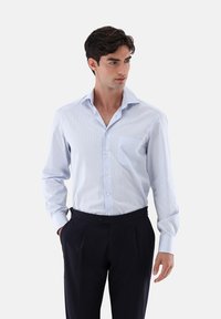 Hellblau gestreiftes Hemd mit Button-down-Kragen, einzelner Brusttasche und langen Ärmeln, kombiniert mit Dunkelblauen Hosen. Glatte Stoffstruktur.