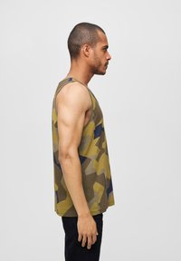 Ermeløs tank topp i olivengrønn med abstrakt kamuflasjemønster i blått og beige. Laget av bomull med en avslappet passform og hip-lengde design.