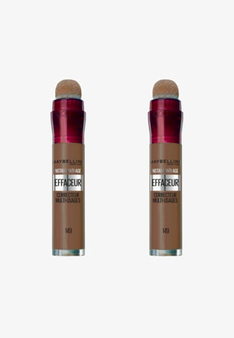 Deux tubes de correcteur Maybelline, marron avec une finition brillante, dotés d'un applicateur en éponge ronde, présentant des accents rouges et un texte argenté.