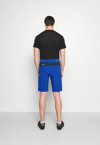 Musta verkkopaita lyhythihaisilla hihoilla yhdistettynä kirkkaan sinisiin shortsit, joissa on tumma vyötärö ja kaksi sivutaskua. Tasainen kangas ja rento malli.