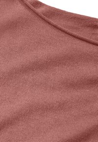 Weicher Strickstoff in einem gedämpften Rosaton, der eine glatte Textur mit feinen Rippen und einem leichten Glanz aufweist. Der Ausschnitt ist rund.