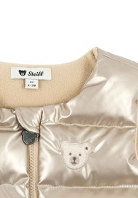 Chaleco de bebé brillante beige con parche de oso de peluche, tirador de cremallera en forma de oso y etiqueta de la marca Steiff, tamaño 62 para 2-3 meses.