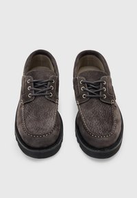 Scarpe in pelle marrone con superficie texturizzata, punta tonda, design con lacci, cuciture a contrasto e suola in gomma nera.