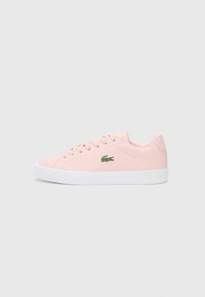 Zapatilla rosa claro con parte superior de sintético liso, suela de goma blanca y logo bordado verde en el lateral. Cierre con cordones y puntera redondeada.