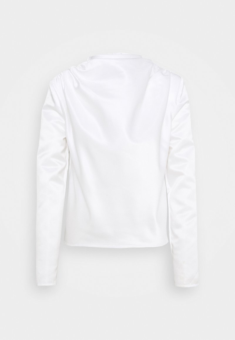 Blouse blanche en satin à manches longues avec un col rond, vue de dos sur un fond clair uni.