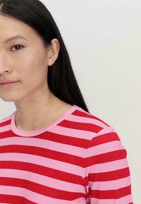 Rood en roze gestreepte lange mouwen shirt met een ronde halslijn, voorzien van een zachte textuur en opvallende afwisselende kleurbanden.