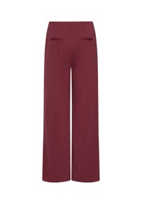 Pantalon taille haute à jambes larges en tissu rouge foncé avec deux poches passepoilées horizontales sur le devant de la taille.