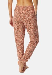 Bloemenprintbroek in koraal met een losse pasvorm, elastische tailleband, zijzakken en zachte stof, met kleine witte en blauwe bloempatronen.