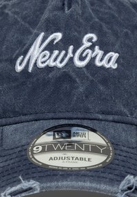 Μπλε σκούρο τζιν καπέλο με λευκό κεντημένο λογότυπο "New Era". Διαθέτει ρυθμιζόμενο λουρί, σχεδίαση σχήματος Α και φθαρμένες λεπτομέρειες.