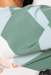 Blusa fluida con un mix di verde, azzurro e motivi floreali. Tessuto morbido con un fit ampio e scollatura rotonda.