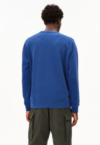 Blauwe sweatshirt met ronde hals, lange mouwen en geribde manchetten. Gemaakt van een zachte stof, het heeft een schoon, eenvoudig ontwerp.