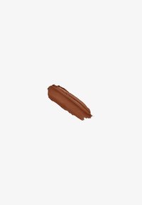 Un seul coup de pinceau lisse d'un produit de maquillage crémeux marron moyen sur fond blanc.