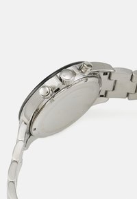 Reloj de acero inoxidable plateado con un bisel redondo negro, dos botones de presión y una elegante pulsera de eslabones. La parte trasera es lisa y sencilla.