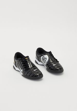 Black athletic shoes with shiny patent leather, featuring a white and silver accent, rounded toe, and a textured upper design with laces.