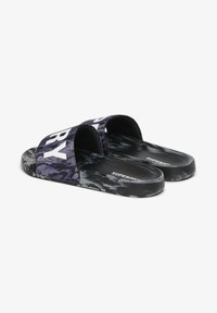 Zwarte en paarse slidesandalen met een camouflagepatroon, voorzien van een brede band met "SUPERDRY" in witte letters. Textuur voetbed.