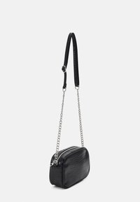 Borsa a tracolla nera con motivo coccodrillo testurizzato, tracolla in catena argentata e chiusura con zip. Forma rettangolare compatta.