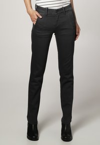 Pantalones oscuros gris, de corte ajustado, con frente plano, bolsillos laterales y pasantes para cinturón. Hechos de una tela suave, con detalles de costura mínimos.