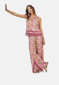 Conjunto de dos piezas con múltiples patrones en rosa, que incluye una blusa sin mangas con flecos y pantalones de pierna ancha, adornados con botones y acentos.