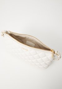 Borsa a tracolla bianca trapuntata con hardware dorato, dotata di chiusura con zip e una tracolla testurizzata, interno foderato in tessuto beige.