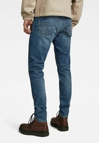 Blå denimjeans med slim fit, med en blekt textur, klassiska bakfickor, och ihop med bruna snörskor.