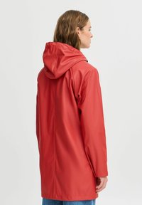 Jachetă impermeabilă roșie cu glugă, textură fină, mâneci lungi și croială dreaptă, prezentată din spate. Design casual cu detalii minimaliste.
