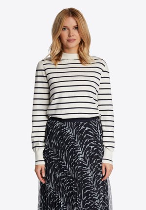 Weißer Pullover mit langen Ärmeln und navyblauen horizontalen Streifen, kombiniert mit einem gefalteten Rock in Schwarz und Grau mit Muster. Schlichtes Rundhalsdesign.