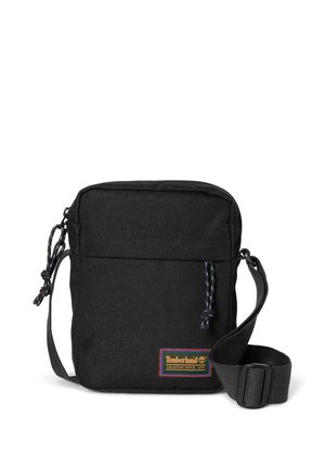 Kleine schwarze Umhängetasche mit Frontreißverschlussfach, verstellbarem Gurt und Timberland-Logo-Patch mit Text "Crafted Since 1973" unten rechts.
