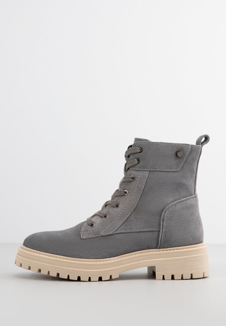 Grauer Knöchelstiefel aus Wildleder mit Schnürdesign, runder Spitze und dicker Gummisohle mit Profil. Mit Rückenzugschlaufe für ein einfaches Anziehen.