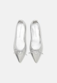 Ballerines métalliques argentées avec un bout pointu, accent de nœud à l'avant et texture lisse. Caractérisées par un design élégant et minimaliste.