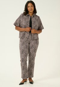 Veste courte en imprimé léopard et pantalon assorti, avec une fermeture à bouton, des manches courtes et une coupe ajustée. Le matériau semble lisse.
