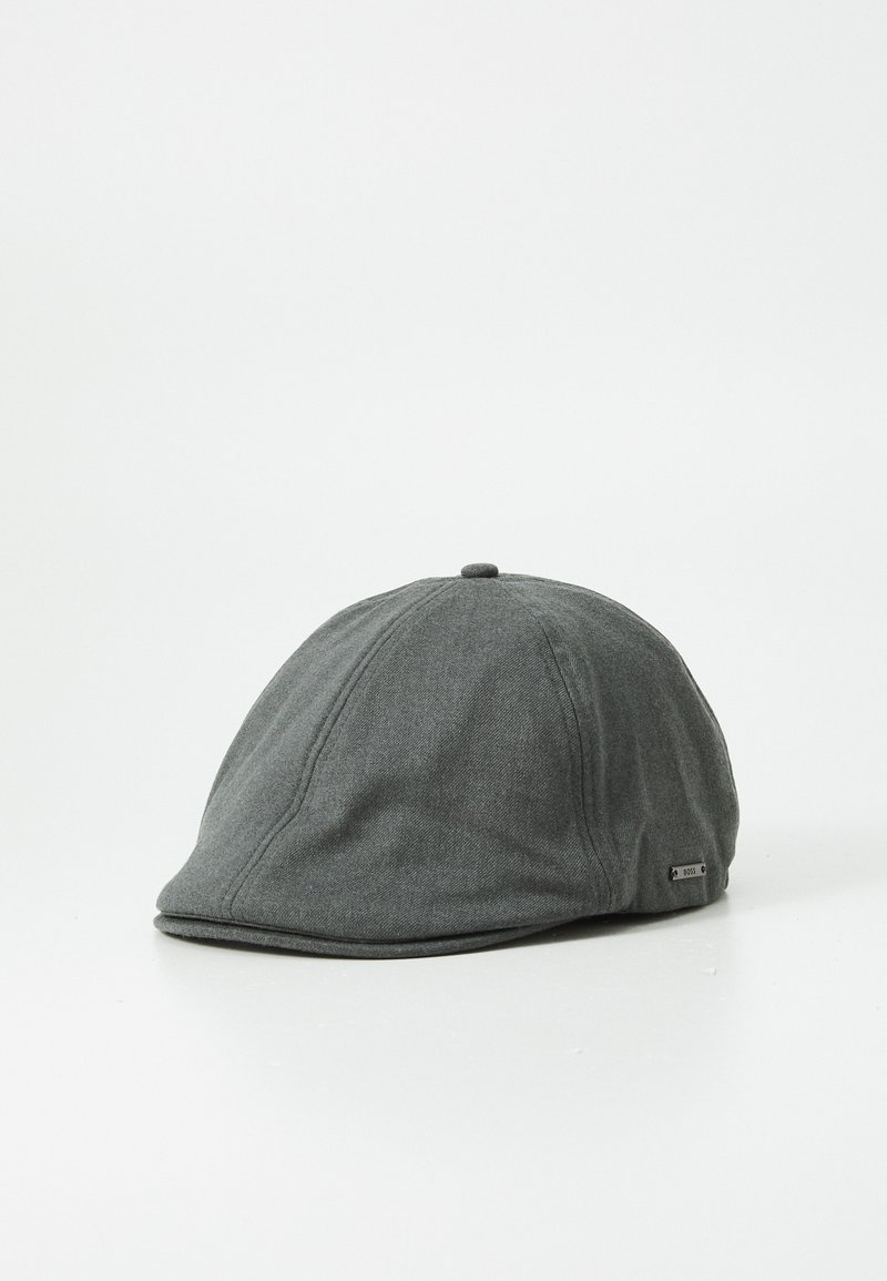 Casquette grise en tissu texturé, avec une couronne arrondie, une visière courbée et une petite étiquette métallique de marque sur le côté.