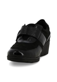 Scarpa a zeppetta nera con una combinazione di materiali lisci e testurizzati, con una larga fascetta in velcro sulla parte superiore e una punta arrotondata.