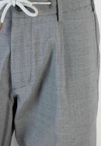 Pantaloni grigi chiari in tessuto strutturato, con chiusura a cordoncino, tasche frontali e design dal taglio classico.