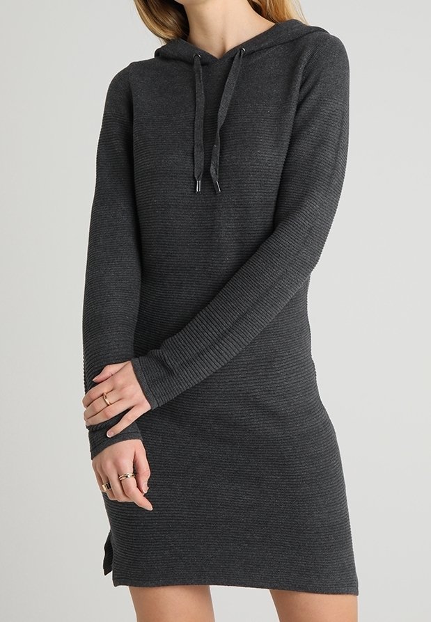 Femme portant une robe à capuche en maille gris foncé à manches longues avec cordons, debout les bras croisés devant un fond uni.