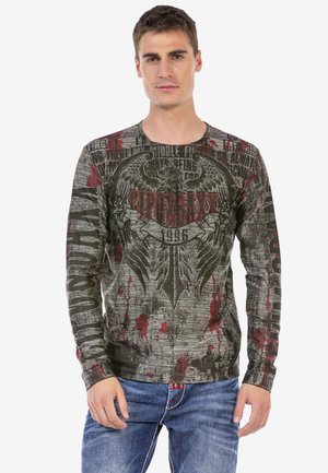 Langärmliges Shirt in Grau und Schwarz mit roten Farbspritzern, mit fettem grafischem Text und einem Adler-Design auf der Vorderseite.