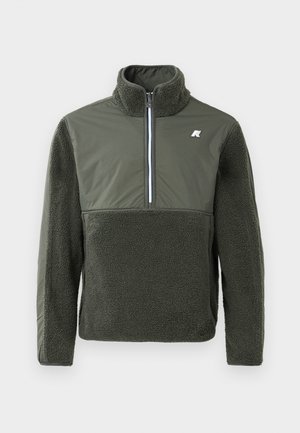 Jersey verde oliva con media cremallera y cuello alto. Textura de forro polar en la parte frontal y las mangas, material suave en la parte superior. Detalle del logo en blanco.
