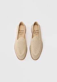 Mocassini in pelle intrecciata beige con punta rotonda e suole marroni, firmati Jacques Solovière, su sfondo bianco.
