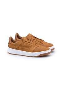 Un paio di sneakers in pelle marrone chiaro con dettagli perforati, lacci e suole in gomma bianca spessa su uno sfondo bianco.