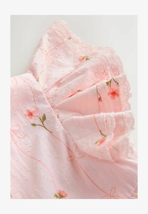 Robe en tissu rose pâle avec broderies florales et motifs texturés. Elle présente des manches volantées et une délicate dentelle le long des bordures.