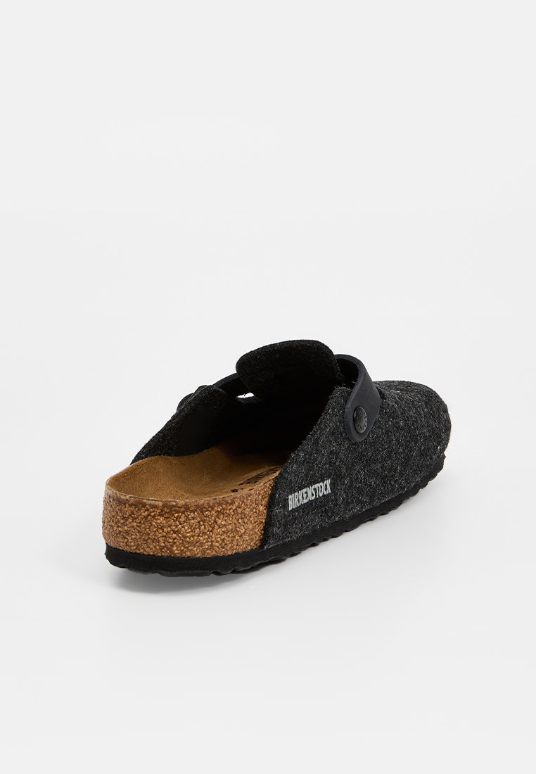 Schwarzer Birkenstock-Block mit Korkfußbett, verstellbarem Riemen und strukturiertem Boden, aus einer hinteren Dreiviertelansicht gezeigt.