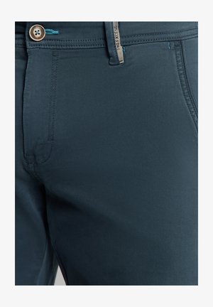 Donker teal katoenmengsel broek met een getailleerde pasvorm, voorzien van een knoopsluiting en contrasterende stiksels. Geen zichtbare patronen of texturen.