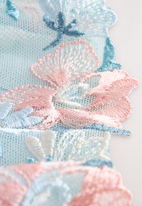 Haftowana koronka z pastelowymi różowymi i niebieskimi kwiatowymi wzorami na jasnym tle z siateczki, z misternym przeszyciem i falistymi brzegami.