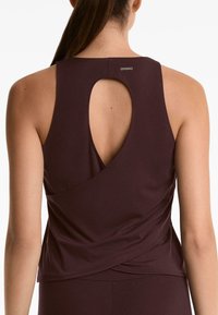 Bordo atletski top s izrezom na leđima, mekanog materijala i drapiranim detaljima sa strana. "OYSHO" logo vidljiv na izrezu.